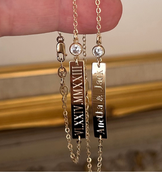 Gold bracelets with engraved names on a neutral background